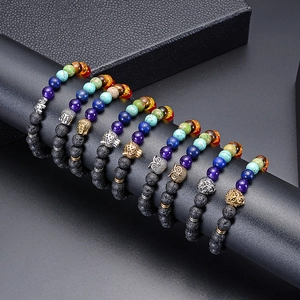 Lava stone chakra bracelets set with lion, owl, and buddha head charms on a black display