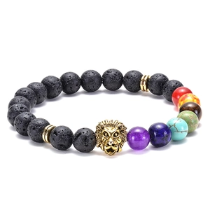 Detailed view of black lava beads and a golden lion head charm on the chakra bracelet