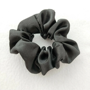 Close-up of a premium black satin scrunchie with a soft glossy texture and high elasticity