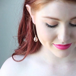 Elegant gold drop earrings with transparent pink crystal pendant on a female model
