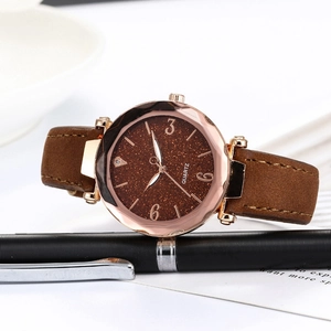Macro shot of rose gold watch case with brown glitter dial and leather strap details