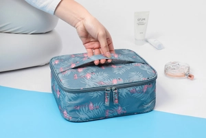 Blue cosmetic travel bag with pink flamingo patterns and top handle detail view