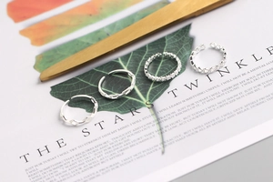 Set of four S925 sterling silver rings with heart and star patterns on a magazine