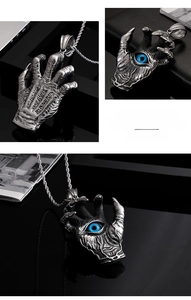 Macro shot of gothic dragon claw pendant in vintage steel with a blue evil eye stone