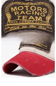 Close-up of distressed red brim and vintage motor racing patch on baseball cap