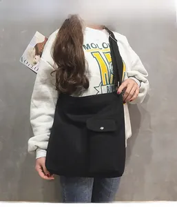 Detail van zwarte canvas crossbodytas met een voorvak met klep en verstelbare riem