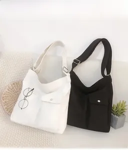 Detail van de canvas crossbodytas met een klepvak en metalen gespsluiting