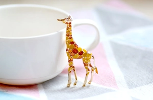 Detailed close-up of a gold-plated giraffe brooch with enamel spots on a ceramic cup