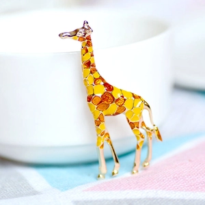 Exquisite gold-plated giraffe brooch with colorful enamel on a white ceramic cup