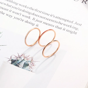 Three minimalist 1mm stainless steel rings in rose gold finish on a creative book background