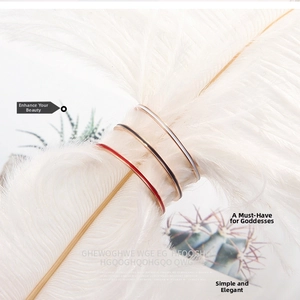 Detailed view of three minimalist 1mm enamel rings in white, black and red on a white feather