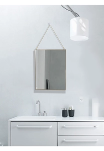 Detail of the golden brass rectangular wall mirror with a minimalist metal frame and chain