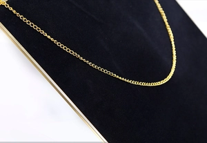 Close-up of minimalist golden brass chain texture on professional black velvet display