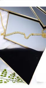 Detalle del espejo hexagonal de latón dorado pulido con cadena soldada y reverso de terciopelo