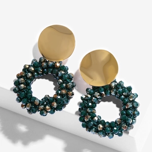 Macro detail of dark green and bronze beaded circular drop earrings with gold metal studs