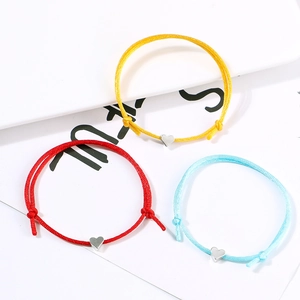Close-up of adjustable woven cord bracelets in red, yellow and blue with heart charms