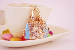 Macro shot of gold handbag keychain with blue enamel and rhinestones in a tea cup