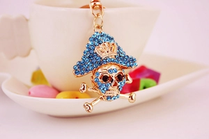 Close-up of golden pirate skull keychain with blue rhinestones and a crown detail