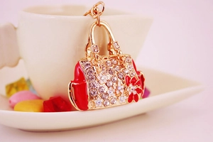Close-up of red enamel handbag keychain with sparkling floral rhinestones and gold finish