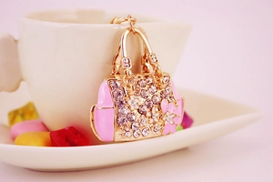 Detail of gold handbag keychain with pink enamel flowers and clear rhinestones