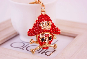 Close-up of golden pirate skull keychain featuring red rhinestones and a gold crown