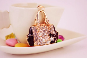 Detailed macro view of a gold handbag keychain with rhinestones and white flowers
