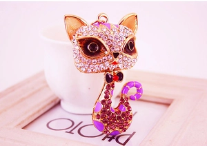 Macro view of crystal cat keychain with purple enamel and gold-plated metal details