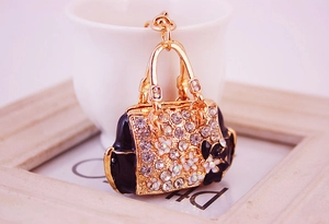 Detail shot of golden handbag keychain with black enamel and sparkling floral rhinestones