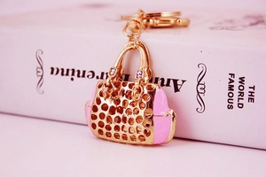 Detailed close-up of a gold-toned handbag keychain with pink enamel and sparkling rhinestones