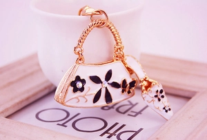Close-up of golden keychain with white enamel handbag and stiletto shoe pendants