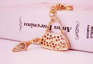 Macro shot of gold high-heeled shoe and handbag keychain with rhinestones