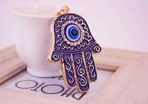 Macro detail of Hamsa Hand pendant with blue enamel, evil eye, and sparkling rhinestones