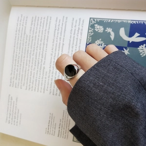Close-up of 925 sterling silver ring with oval black stone on a classic suit sleeve