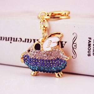 Golden flying pig keychain with blue rhinestone gradient and white wings charm