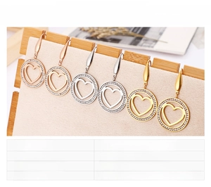 Trois paires de boucles d'oreilles cœur évidées avec cristaux sur support en bois