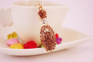 Close-up of a golden bowling pin keychain with brown rhinestones and sparkling details