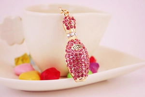 Close-up of golden bowling bottle pendant with pink rhinestones and LUCKY engraving
