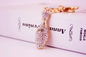 Macro view of rhinestone-studded bowling pin keychain resting on a vintage book spine