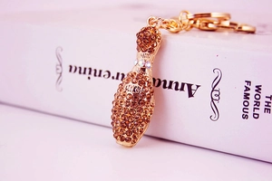 Macro shot of gold bowling pin keychain with brown crystals and CUKY engraving details