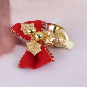 Close-up of a red Christmas bow with golden edges, decorative leaves, and a metal bell