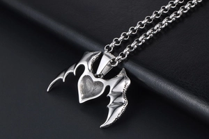 Macro shot of silver heart and bat wing pendant necklace with polished metal texture