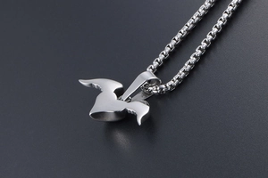 Macro shot of silver wing heart pendant in polished titanium steel on grey background