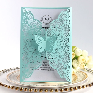 Detail of laser-cut butterfly invitation with intricate lace texture and white insert card