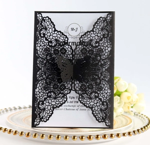 Detail view of a black laser-cut butterfly wedding invitation on a white decorative plate