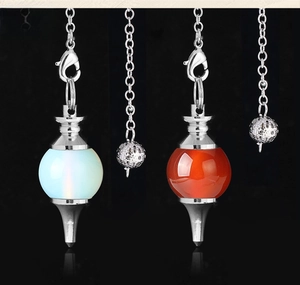 Macro shot of opal and carnelian gemstone pendulum pendants with silver metal chains