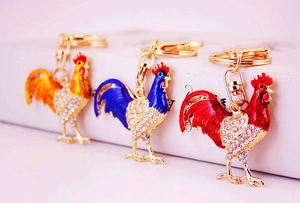 Three colorful zodiac rooster metal keychains with sparkling crystals and gold plating
