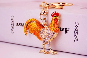 Detailed view of rooster keychain with sparkling rhinestones and colorful enamel