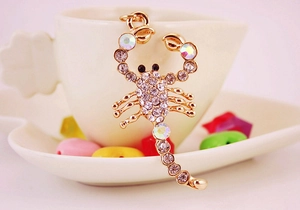 Detailed view of scorpion keychain with crystal rhinestones hanging on a ceramic cup