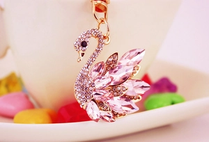 Macro view of swan keychain with pink crystals and polished gold metal details