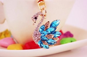 Macro shot of a golden swan keychain featuring blue teardrop gems and clear rhinestones